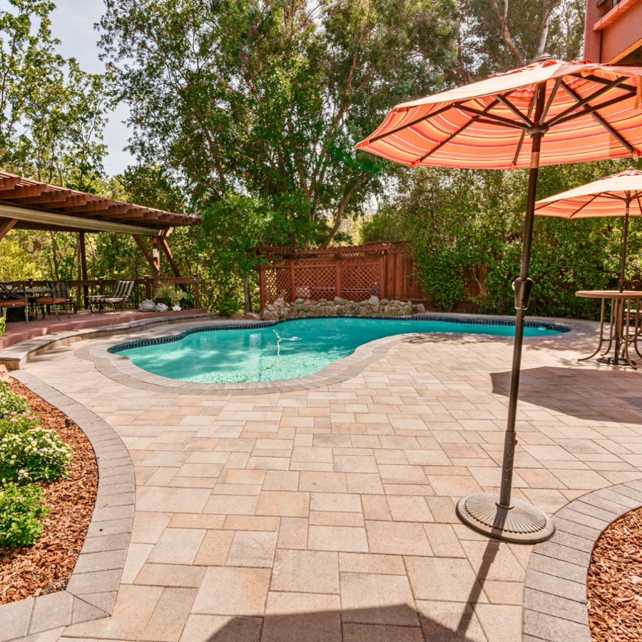 Paver pool deck with umbrella and lounge seating built by BBP Pavers