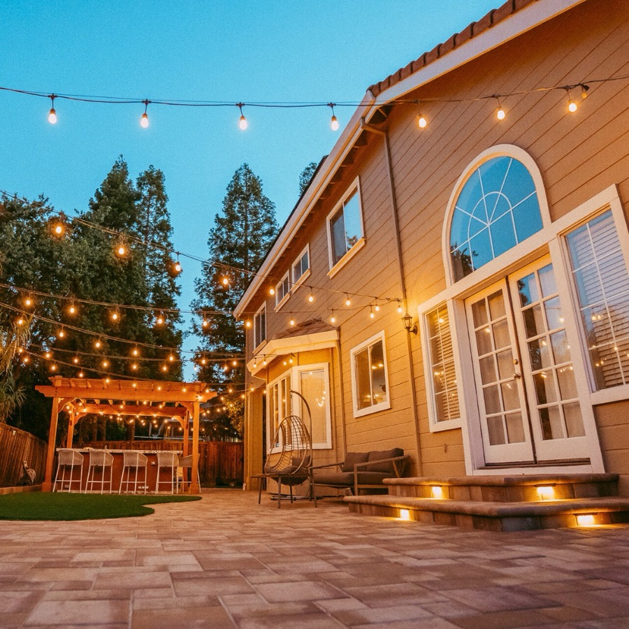 Paver patio with string lights on a two-story Bay Area home
