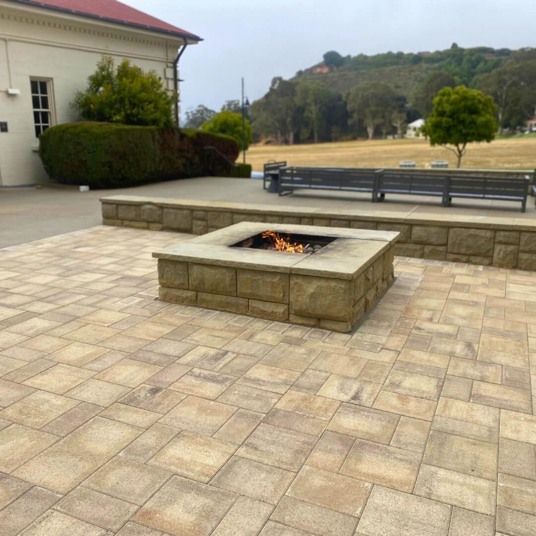 A backyard brick paver patio featuring a custom fire pit and integrated seating area A backyard brick paver patio featuring a custom fire pit and integrated seating area